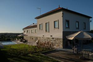 a building with a table and an umbrella at Quinta de Vodra in Seia