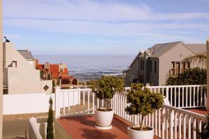 a balcony with potted plants and the ocean at Charming Fisante house in Hermanus