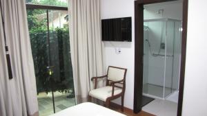 a bathroom with a chair and a glass shower at Pousada by Rieger in Blumenau