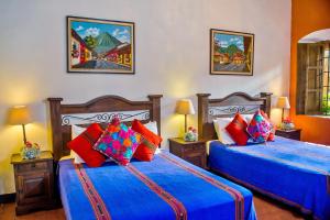 2 camas en una habitación con almohadas azules y rojas en Hotel Casa Antigua by AHS, en Antigua Guatemala