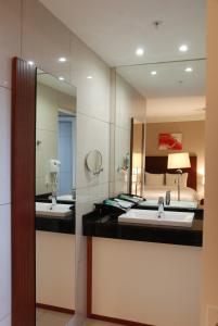 a bathroom with two sinks and a large mirror at Ramada by Wyndham Princess Paramaribo in Paramaribo