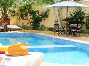 einen Pool mit einem Tisch und einem Sonnenschirm in der Unterkunft Kingfishers Apartments in Bijilo