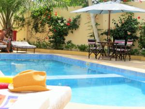 a swimming pool with a table and an umbrella at Kingfishers Apartments in Bijilo