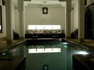 a swimming pool in a building with a table and chairs at Riad First in Marrakesh