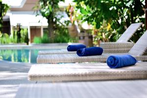 a row of chaise lounges with blue rolled up towels on them at Deevana Krabi Resort in Ao Nang Beach