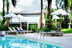 a swimming pool with chairs and umbrellas next to a house at Deevana Krabi Resort in Ao Nang Beach