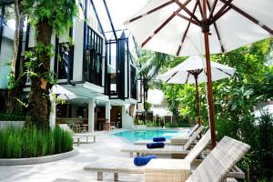 a pool with chairs and umbrellas next to a building at Deevana Krabi Resort in Ao Nang Beach