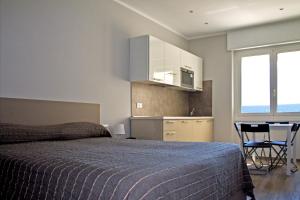 a bedroom with a bed and a table and a kitchen at Residence Fanny in Alassio