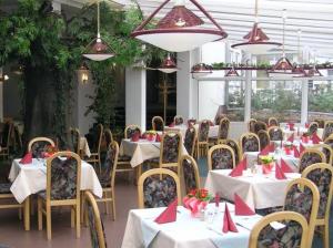 un restaurante con mesas y sillas con servilletas rojas en Waldhotel Seelow, en Seelow