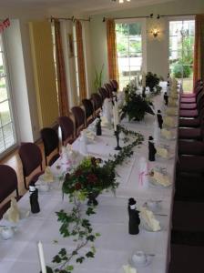 einen langen Tisch in einem Zimmer mit weißen Tischen und Stühlen in der Unterkunft Waldhotel Seelow in Seelow