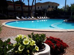 a swimming pool with chairs and flowers in front of it at Thairè Resort in Castel Volturno