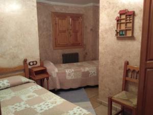 um pequeno quarto com 2 camas e uma cadeira em Casa Marzo em Angüés