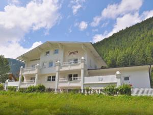 ein großes weißes Gebäude mit einem Hügel im Hintergrund in der Unterkunft Saffretta Ferienwohnungen in Ischgl