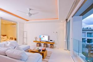 a living room with a white couch and a tv at Chi Samui Resort in Bophut