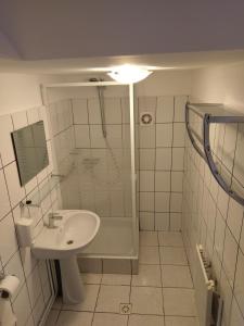 a white bathroom with a sink and a shower at Aterman House in Vlădeni