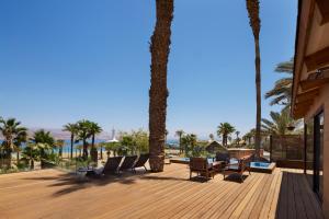 a wooden deck with chairs and palm trees on a beach at Orchid Eilat Hotel in Eilat