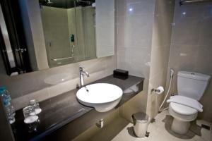a bathroom with a sink and a toilet and a mirror at Samala Hotel Jakarta Cengkareng in Jakarta