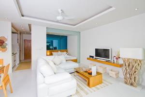 a living room with a white couch and a tv at Chi Samui Resort in Bophut