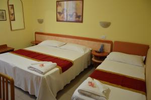 a hotel room with two beds and a table at Hotel Carolin in Rimini