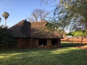 a thatch roofed house on a grass field at Baobab Lane Lodge in Marnitz