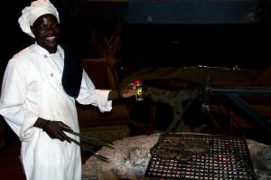 a man cooking food on top of a grill at Baobab Lane Lodge in Marnitz