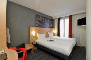 パリにあるイビス パリ ヴォージラール ポルト ド ヴェルサイユの白い大型ベッドと椅子が備わるホテルルームです。