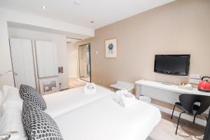 Habitación de hotel con 2 camas y TV en Petit Palace Puerta del Sol, en Madrid