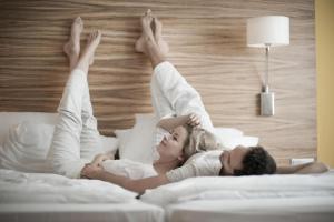 Ein Mann und eine Frau liegen auf einem Bett mit den Händen in der Luft in der Unterkunft Reduce Hotel Vital in Bad Tatzmannsdorf