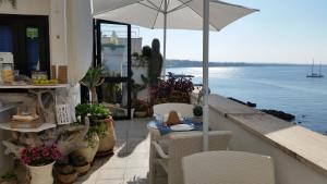 a table with an umbrella on a balcony next to the water at B&B Punta Cutieri in Gallipoli