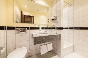a bathroom with a sink and a toilet and a mirror at Garner Hotel Cologne Porz - Airport by IHG in Cologne