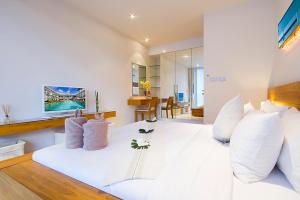 a white bedroom with a large white bed with white pillows at Chi Samui Resort in Bophut