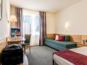 a hotel room with a bed and a couch at Hotel Am Moosfeld in Munich