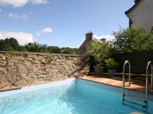 una piscina frente a un muro de piedra en Luxurious Villa in Pont-Aven with Private Pool, en Pont-Aven