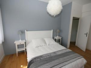 Un dormitorio con una cama blanca con dos mesas y una lámpara de araña. en Luxurious Villa in Pont-Aven with Private Pool, en Pont-Aven 32 fotos más