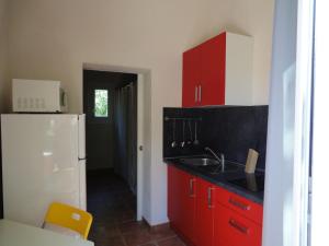 ポッジョ・メッザナにあるCosy Holiday Home in Poggio Mezzana on the Beachsideのキッチン(赤いキャビネット、白い冷蔵庫付)