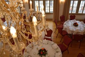 Habitación con mesas y sillas blancas y lámparas de araña. en Hotel Zofingen en Zofingen