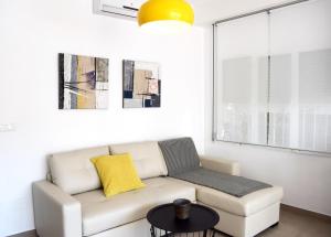 a living room with a white couch and a yellow pillow at El Jardin BeNerja in Nerja
