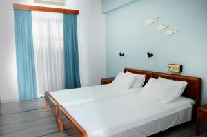 a bedroom with two beds and a large window at Hermes in Kalymnos