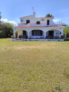 a white house with a large yard in front of it at Villa Adelina in Porto Columbu - Perdʼe Sali