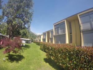 une rangée d'immeubles d'appartements avec des buissons devant eux dans l'établissement Camping Villaggio Paradiso, à Domaso