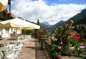 a patio with tables and chairs and flowers at Hotel Val Di Fassa in Soraga