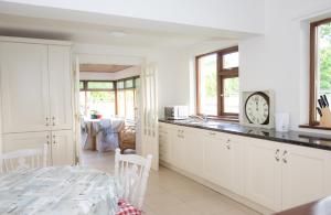 a kitchen with white cabinets and a clock on the counter at Luskin's in Cong