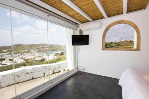 a bedroom with a bed and a large window at Anixi Lounge Suites - Adults Only in Ornos