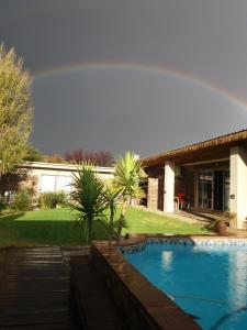 a rainbow over a house with a swimming pool at Skietberg Lodge in Colesberg