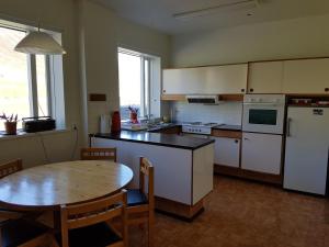 een keuken met een tafel en een witte koelkast bij Húsabakki Guesthouse in Dalvík