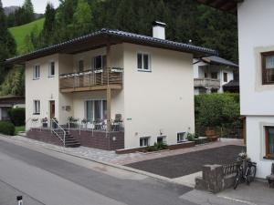 a white house with a balcony on a street at Ferienwohnung Dolomitenheim in Außervillgraten