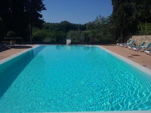 a swimming pool with chairs and blue water at Hotel Pescille Country House - Tuscany Charme in San Gimignano