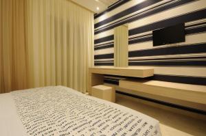 a bedroom with a bed and a tv on a wall at Louloudis Fresh-Adults Only in Skala Rachoniou