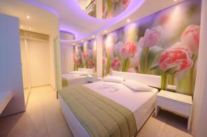 a bedroom with three beds with pink flowers on the wall at Louloudis Fresh-Adults Only in Skala Rachoniou