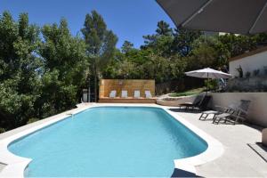 a swimming pool with chairs and an umbrella at Villa Roca in Les Issambres